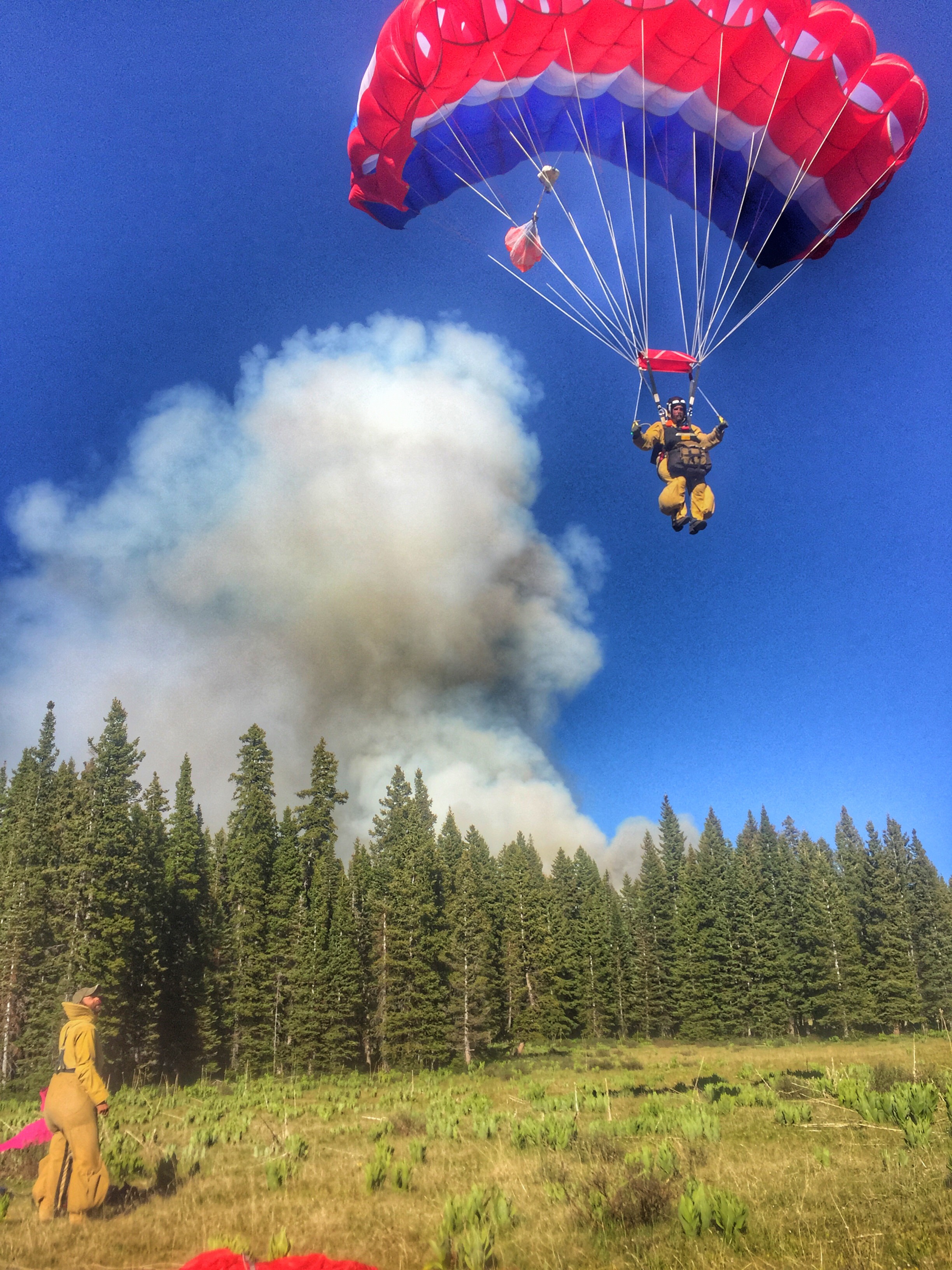 A smokejumper landing in a meadow.